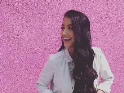 Kaitlin Nowak is doing a candid shot with purple wall in the background.